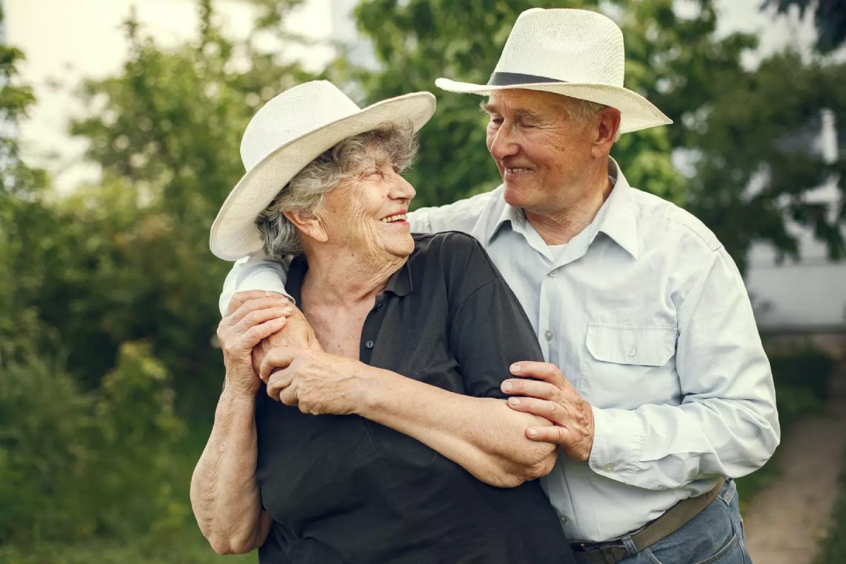 Un couple âgé et souriant représente la tendresse et la complicité d’un amour durable, illustrant les 65 ans de mariage, appelés noces de palissandre.